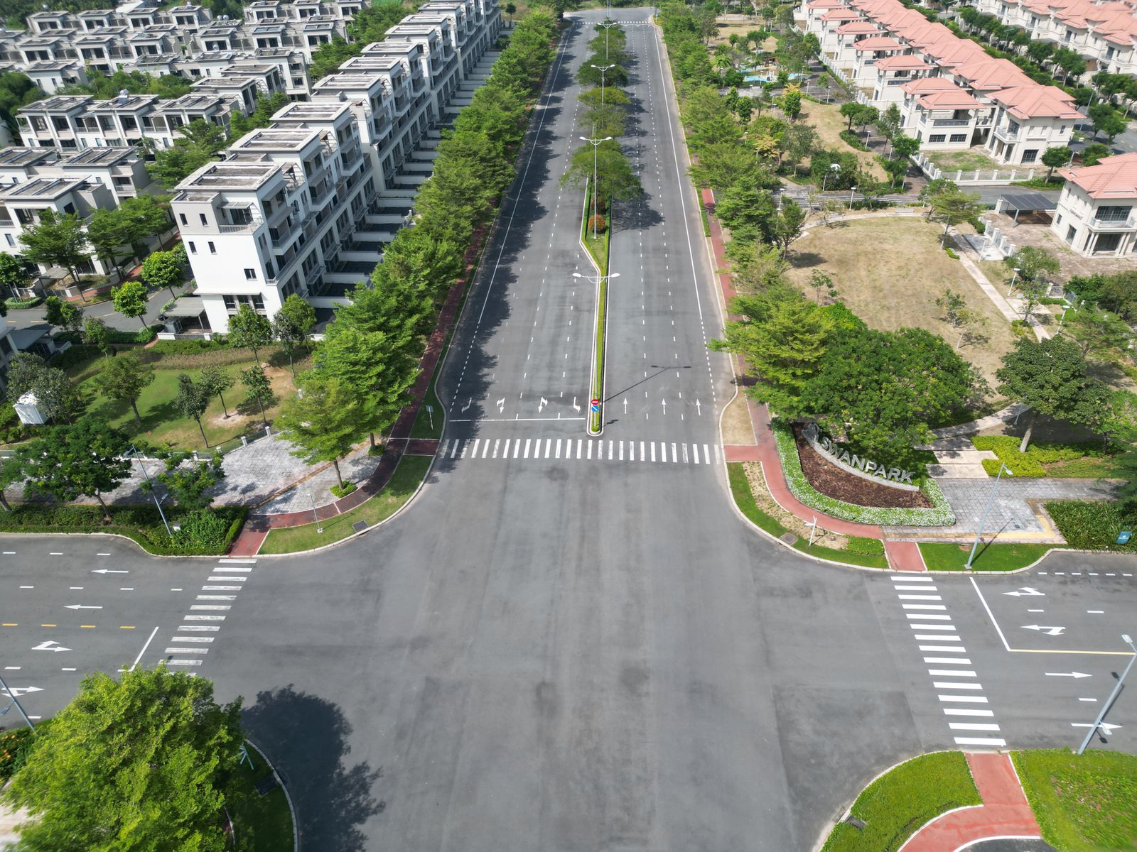 Nút giao đường rộng giữa khu nhà phố thấp tầng nhiều cây xanh, nhìn từ trên cao